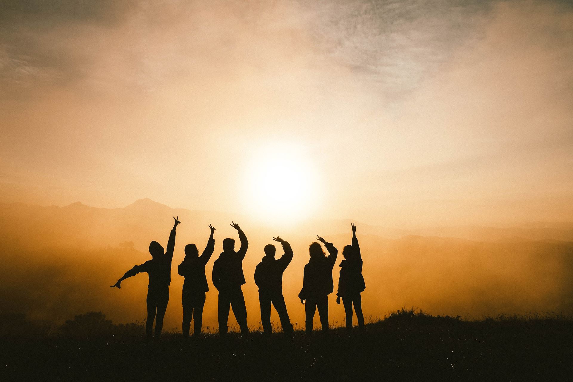 a group of people standing in front of a sunset